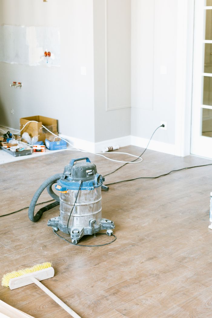 about-us-01 A vacuum and assorted tools in a room being renovated, highlighting home improvement work.